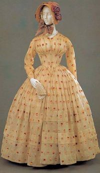 Winsome late 1840s-early 1850s dress with fitted sleeves, dropped, pointed waist, and full, tiered bell skirt.