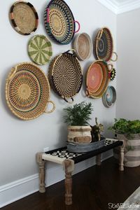 This colorful, boho, African basket gallery wall is an unexpected way to display art! She found affordable, hand woven baskets along with woven bench to create a unique wall. Baskets from Ghana add color and personality to the gray walls in this dining room and see her unique way of hanging baskets. • storage for decoraing & organizing • ideas for living room •