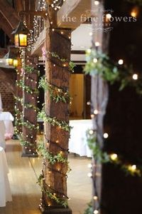 The pillar uprights at the Tithe Barn in great Fosters, decorated with ivy and fairy lights. From wedding reception at Great Fosters Le Jardin Weddings | Utah Wedding and Reception Center | Sandy | Salt Lake City | Winter Wedding | Christmas | Holidays #holidaywedding #christmaswedding #winterwedding #lejardinweddings