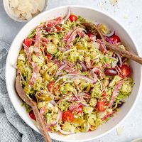 Gorgeous Italian chopped salad recipe loaded with shredded brussels sprouts, chickpeas, veggies, salami, olives, pepperoncini and delicious cheeses. This flavorful and easy Italian chopped brussels sprouts salad is tossed in a light Italian dressing and makes the perfect hearty lunch or fresh dinner! #salad #brusselssprouts #healthydinner #healthylunch #glutenfree #mealprep