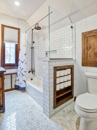 A low wall between the tub and the toilet provides the perfect space for a built-in toilet paper shelf.