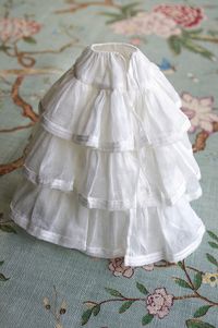 Underwear... On a background of organdy to support the fullness, the petticoat deploys its three cotton voile flounces, each bordered with two rows of silk ribbon.