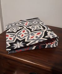 Recouvrir un vieux classeur en mauvais état avec du tissu égyptien et le voilà reparti pour une nouvelle jeunesse. Utilisation de gesso pour recouvrir les parties les plus sombres et de colle en spray pour une prise rapide. Le tissu khayameya "étoile grise" est disponible en boutique.
