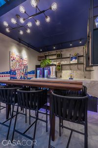 Go Draft Garden – Amanda Andrade. Esse espaço mistura a estética natural com o conceito industrial. Inspirada pelo tema de 2018 da CASACOR, A Casa Viva, a profissional utiliza materiais como madeira e granito e uma iluminação azulada para criar uma atmosfera sincrética.