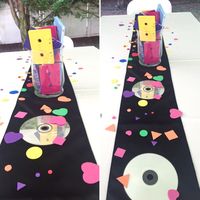 90's theme party centerpiece. Found some old CD's in the basement (which we all know we won't use anymore), placed them upside down on both sides of the vase along the table runner. Make sure to clean the CD's for scratches like you did in the old days when you wanted to listen to your favorite tunes. Makes them look nice and shiny on the tables.