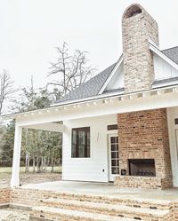 Outdoor fireplace - white farmhouse - black windows - exposed rafters on porch (not sure what it's called)