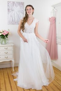 Ein tiefer Rückenausschnitt, transparente Spitze im Oberteil und verspielte Flügelärmchen machen das Oberteil von Antonia zu etwas ganz Besonderem. Der federleichte Rock, aus einer Kombination von Chiffon und Tüll verleiht dem Kleid einen Hauch von Vintagezauber. Die klassische A-Linie eignet sich perfekt für deine Sommerhochzeit und kann - so wie all unsere Designs - auch nach deinen Wünschen mitgestaltet werden.