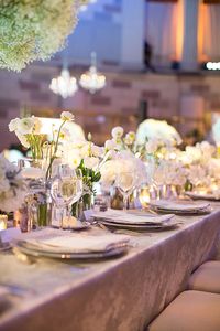 This table is covered with ikat-patterned metallic linens and topped with trumpet vases of baby's breath. Smaller arrangements in mercury glass vases of white roses, peonies, and sweet peas added depth to the tables.