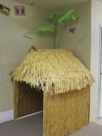 grass hut-- cardboard with roof made from faux grass skirts... walls covered with plastic tablecloth with bamboo print?