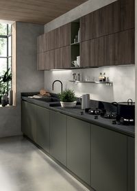 The harmonious appeal of Mineral Green used for the recessed grip profiles, base units and plinths constitutes an extremely classy detail: this matt lacquered colour distinguishes the operational areas of the kitchen, and matches the textured feel of Calce Nero Porcelain Stoneware to perfection. The wall units and tall units are in Garden Walnut decorative melamine (with vertical grain)