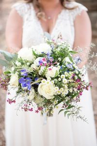 Moon Valley Farm September Wedding in Stafford Virginia | Northern Virginia Wedding Photographer | Emily Marcella Photography | Bride poses with wildflower wedding bouquet that has mini daisies, navy flowers, pink wax flowers, white roses, and greenery. Wildflower bouquet, navy blue wedding details, farm wedding, rustic wedding ideas #virginiawedding #fallweddinginspiration #northernvirginiaphotographer