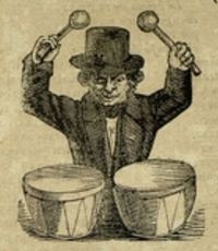 Hombre con sombrero de copa tiene los brazos en alto sosteniendo los mazos con los que toca dos tambores.