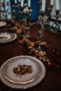 Decoración de una mesa con platos antiguos y candelabros con velas