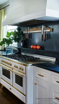 ASHLEY GILBREATH INTERIOR DESIGN: A chef's dream kitchen with soapstone counter tops and backsplash, custom shiplap range good and Ilve white gas range with beautiful brass hardware. This Southern kitchen is perfect for hosting and cooking for large crowds.