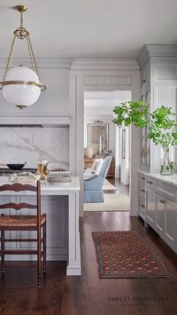 ASHLEY GILBREATH INTERIOR DESIGN: A beautiful play of high and low on the millwork detail within this Georgia lakehouse kitchen. Cabinets built to resemble furniture gives a historic sense to the space and the warm of the walnut stained hardwoods added character and charm. architect Brandon C Ingram