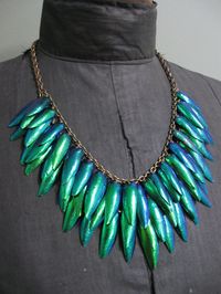 I decided to bring back one of my most popular designs for Fall 2011. Part of a limited series using Thai jewel bettle wings. Amazingly iridescent scarab beetle wings from Thailand are layered to form a glittering bib in this lightweight statement necklace design. The bib flows from collarbone to collarbone and drops to the top of the bust. The chains are hand-oxidized vintage brass. The shortest strand sits at 18" (just above the bust on an average woman). Longest chain cascades to 21" (r