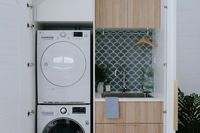 It might be small on space but NOT in style! This European style laundry features a stunning blue-green fish scale or fan shape tile, timber joinery and hanging rail. Dryer stacked on top of washing machine in this compact laundry. Small space laundry renovation. Click through to the blog for all the photos and supplier details.