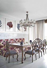 In this Miami dining room designed by Sid Bergamin, a bespoke tiled wall offers a graphic, glossy backdrop to a plush, tufted banquette covered in a rosette pattern from Pierre Frey. The dining table and chairs are from Jalan Jalan, and the chair upholstery is Raoul Textiles. The coral prints, a nod to the nearby ocean, are from Jalan Jalan, and the diaphanous drapery fabric is Ralph Lauren.