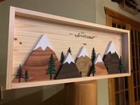 "Seek Adventure 3D Trees & Mountain Range - Handmade Wood Sign This sign measures 13.5\" high by 31.5\" wide when finished. This sign is the perfect addition to your home decor and makes a great gift as well! Display it anywhere in your home. This piece is rustic, yet elegant in design. It makes the perfect gift for the outdoor adventurer in your life. The color combination is made to compliment almost any home decor. This sign is made out of pine wood. The mountains are hand cut, and sanded