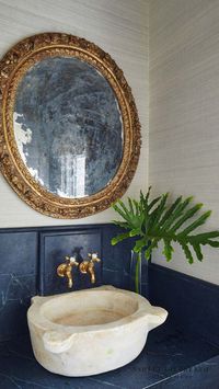 ASHLEY GILBREATH INTERIOR DESIGN: A stunning, unique half bath in interior designer's, Ashley Gilbreath, personal Alabama home. With a beautiful built-in soap stone vanity and backsplash, stone sink, brass wall mount faucet, grasscloth wall covering, and one-of-a-kind antique European round mirror.