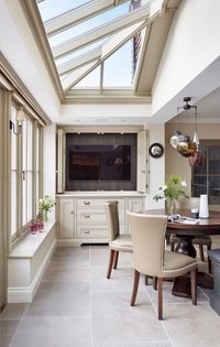 Casual upholstered seating area built into one end of the kitchen island, with hanging pendant lights to accentuate the orangery.