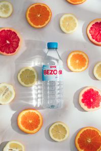 Botella de agua Bezoya rodeada de rodajas de naranja, limón y pomelo.