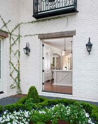 Gorgeous courtyard off of kitchen with painted white brick home exterior and gray gravel walkways.