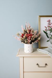 Jarrón con flores preservadas sobre una cómoda
