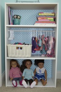 Doll Storage. $20 bookshelf from Target, add tension rod for hanging doll clothes (hangers from Amazon). Add cute contact paper to the back BEFORE nailing it to the bookshelf.