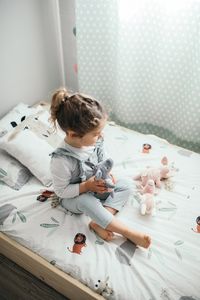 Niña pequeña jugando en su cama con los peluches de los tres cerditos