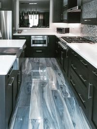 Artistic Tile I Unique tiles combine in this eclectic Stamford, Connecticut kitchen! On the floor, Kauri wood-look porcelain planks in Tasman Blue lengthen the space, coordinating beautifully with the varied tones of our Jazz Glass Scales Blue Blend backsplash. This excellent interior design was envisioned by our White Plains showroom associate, Melissa Puchalski!