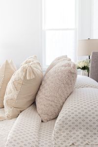 Tips and tricks for adding interest to layered neutral bedding. Includes suggestions for pillow placement and exactly how to place the layers.