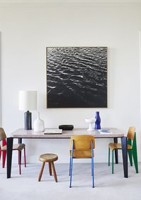 A space for work or dining is discreetly tucked into one side of the living room. The granite-topped table and Standard Chairs are all by French modernist designer Jean Prouvé (find re-editions of Prouvé’s work at Vitra, vitra.com) and the wooden stool is by Charlotte Perriand. The table lamp is by Georges Jouve, as are the white ceramics; the blue vase is by French modernist ceramicist Suzanne Ramié. The artwork on the wall above the table is by German contemporary artist Frauke Eigen.