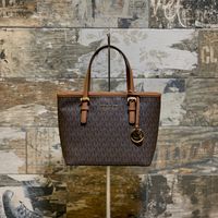 Borsa Michael Kors Small modello Jet set colore Brown con effetto monogramma MK. Logo pendente in metallo dorato. Da portare a mano o con tracolla lunga.