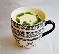 5-minute chickpea flour soup in a black and white mug, drizzle with prepared pesto