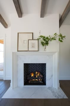 Rustic wood ceiling beams are fixed to a ceiling over a beautifully styled white beveled fireplace mantel accenting a white marble surround and a white marble hearth contrasted with a black herringbone firebox. Fireplace Mantle Decor, Living Room Remodel, Marble Fireplace Surround