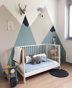 a baby's room with mountains painted on the wall and a crib in the foreground