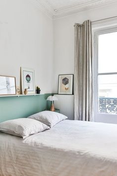 Une tête de lit vert d'eau égaye cette chambre toute blanche