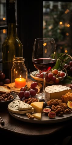 a table topped with cheeses, crackers and wine next to a glass of red wine