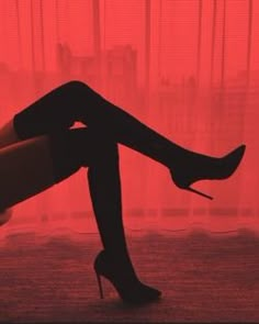 a woman's legs in high heeled black shoes with red light behind them