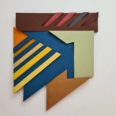a piece of art that is made out of different colored paper shapes and lines on a white wall