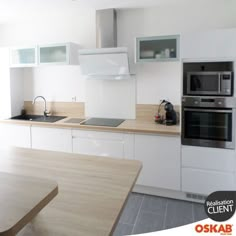 Cuisine scandinave blanche brillante avec plan de travail en bois clair, ilot séparateur avec plan surélevé, porte avec système de passe main, meubles hauts vitrés, fond de hotte en verre blanc - www.oskab.com Updated Kitchen, Kitchen White, Kitchen Updates, Diy Kitchen Decor, White Scandinavian Kitchen