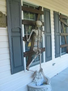 halloween craft idea cardboard affixed to window to make it look boarded up and skeleton propped to look like its trying to get in