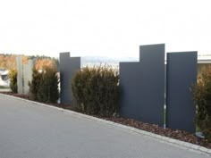 the fence is made of metal and has plants growing on it, along with other shrubs