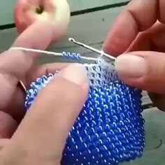 two hands are working on an object with yarn