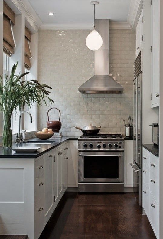 Kevin Dakan kitchen via Remodelista. Small white classic kitchen with glazed tile statement wall and dark counters. #smallkitchen #ushape #kitchendesign