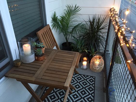 Apartment small balcony decor ideas and design. Balcony garden with candles, string lights, and tropical plants. Perfect for hot summer nights.