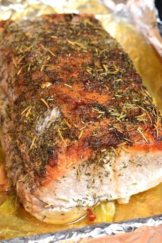 Pork Loin in the oven. This juicy and tender pork loin is baked on a bed of veggies for extra flavor and moisture, stuffed with garlic cloves, and rubbed with an herb mixture. #pork #maindish #porkloin #dinner