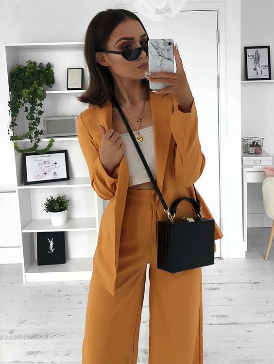 Selfie perfeita: 10 capinhas de celular trendy que dão um up nas fotos de espelho. Terninho, blazer amarelo, calça de alfaiataria amarela, top cropped branco, bolsa quadrada, mini óculos, capinha de mármore carrara