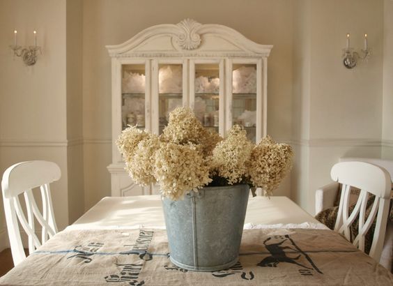 Romantic feminine shabby chic dining room/white painted buffet and hutch/Swedish wood chairs/German grainsack (A Beautiful Mess)/galvanized bucket with hydrangea/crystal sconces/monogram stenciled letters on wall/Hello Lovely Studio